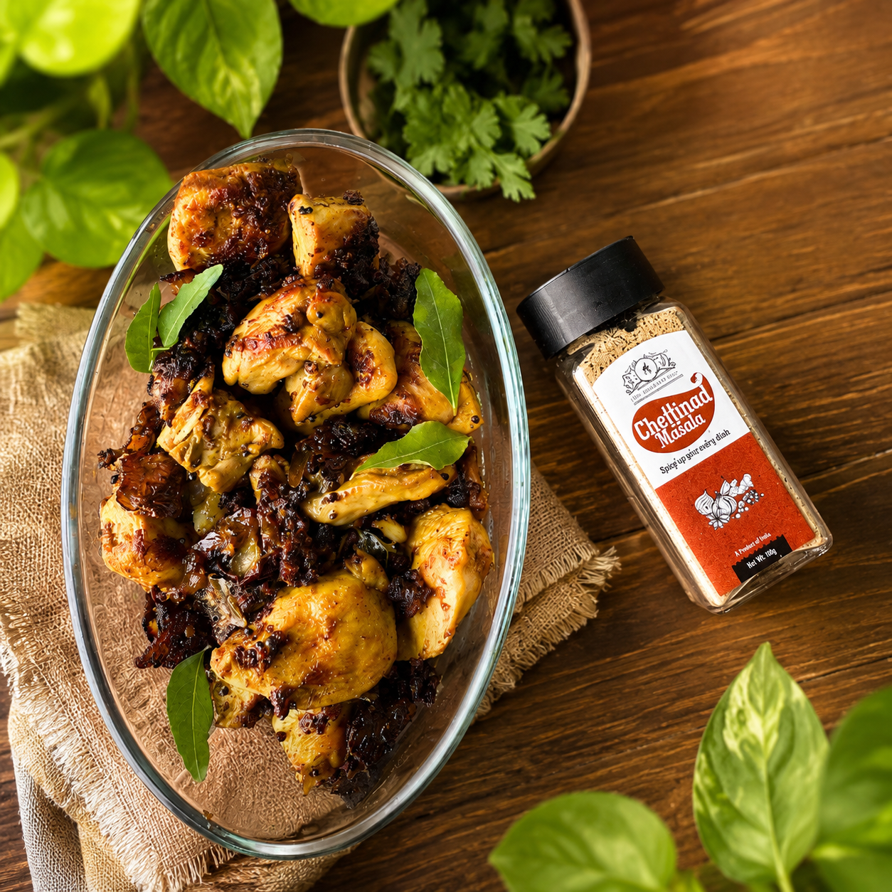 Spicy chicken platter prepared with Chettinad Masala by The MMasala Box Co served on rustic wooden background with fresh curry leaves and premium spice jar